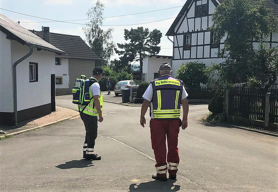 Sven Skaberna (links) und Hans-Peter Bendner bei der Erkundung des Dorfes Harscheid. Sie gehen auf Menschen zu und erkundigen sich nach deren Befinden. (Foto: Kerstin Skaberna / BRK)